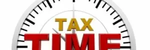 Image of a clock partially shown with the words "TAX TIME" in bold red and yellow letters in front of it.