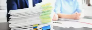 Stack of documents on table and blurred workers in office